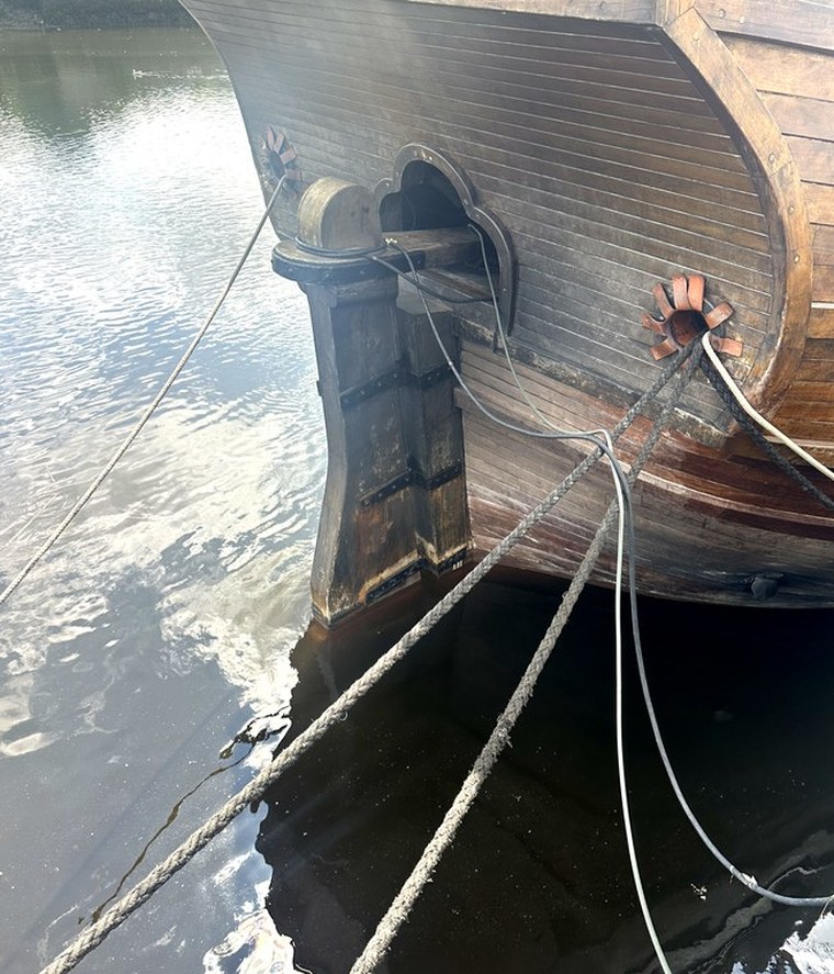 Exterior stern of the Nao Santa María showing the wooden rudder hinged to the hull and the tiller opening above