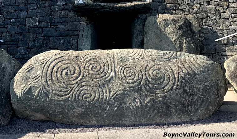 Kerbstone 1 at Newgrange with carved triple spirals before the passage entrance and roof box
